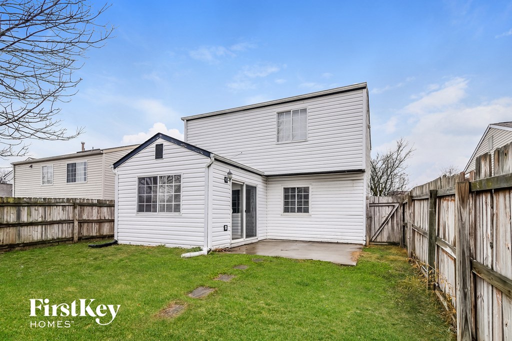 a backyard with a white house and a wooden fence