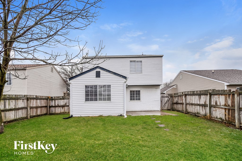 a backyard with a white house and a wooden fence