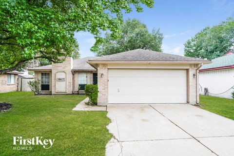 A house with a garage and a tree in front.