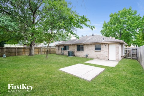 A house with a lawn and trees in the background is for sale.