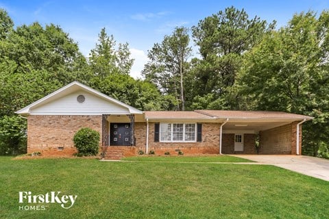 a brick house with a green lawn and trees