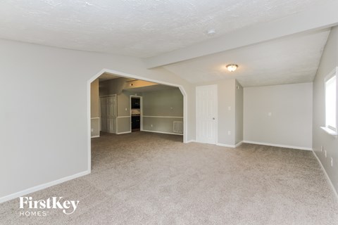 a spacious living room with carpet and a door to the kitchen
