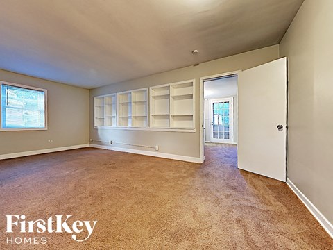an empty living room with white shelves and a door to a hallway