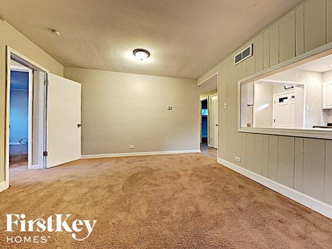 an empty living room with carpeting and a mirror