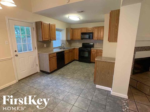 A kitchen with wooden cabinets and a tiled floor.