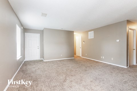 a spacious living room with carpet and a door to a bedroom
