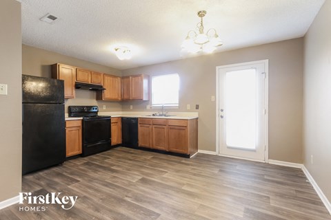 a kitchen with wood flooring and wooden cabinets and black appliances