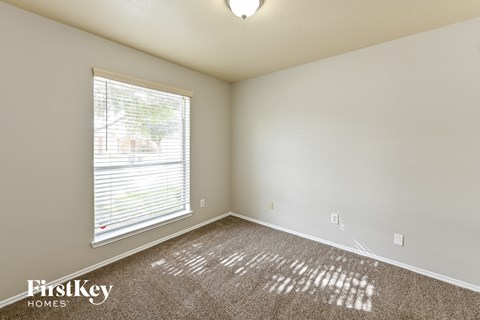 the living room of an apartment with a large window and carpet