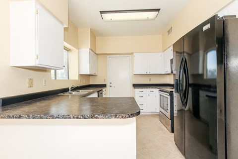 A kitchen with a black counter top and stainless steel appliances.