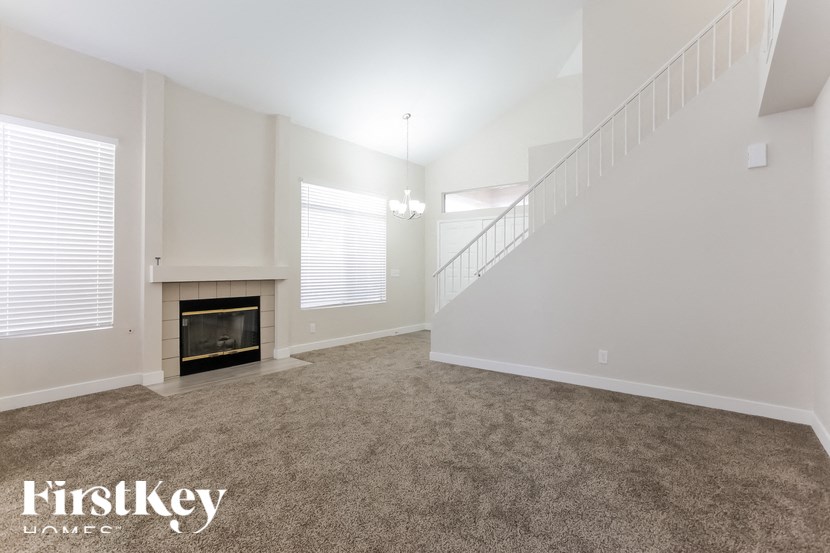 A spacious living room with a fireplace and a staircase.