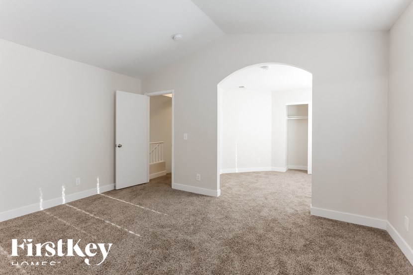 A spacious room with a carpeted floor and white walls.