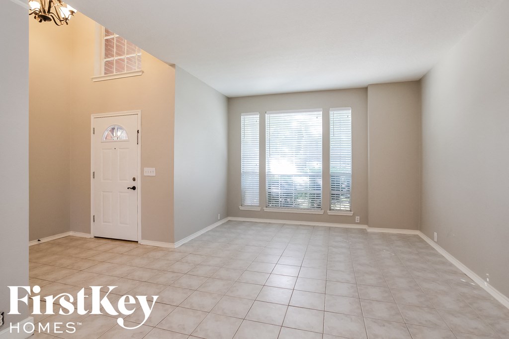 an empty living room with a white door and window