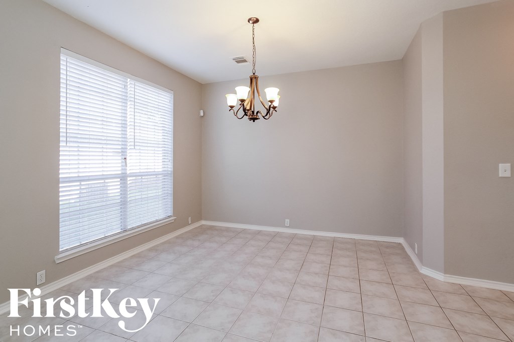 an empty dining room with a large window and a chandelier