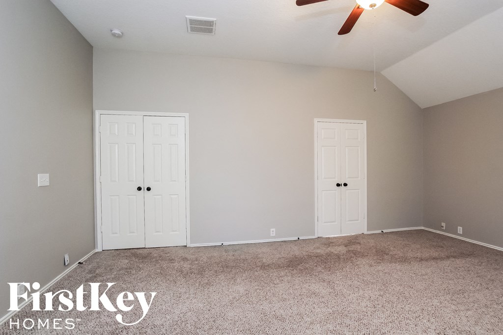 a bedroom with two doors and a carpeted floor and a ceiling fan
