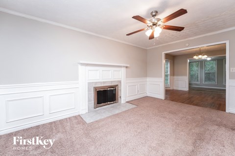A well-lit room with a fireplace and a ceiling fan.