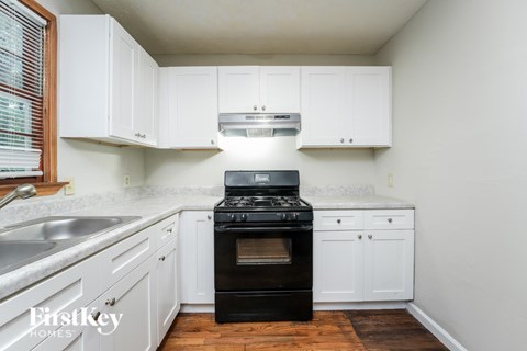 A kitchen with white cabinets and a black stove top oven.