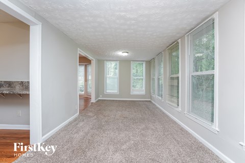 A spacious room with a carpeted floor and a fireplace on the left side.