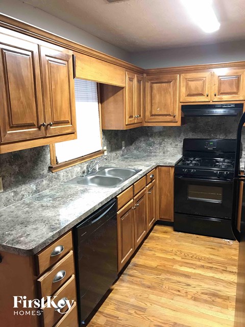 A kitchen with wooden cabinets and black appliances.