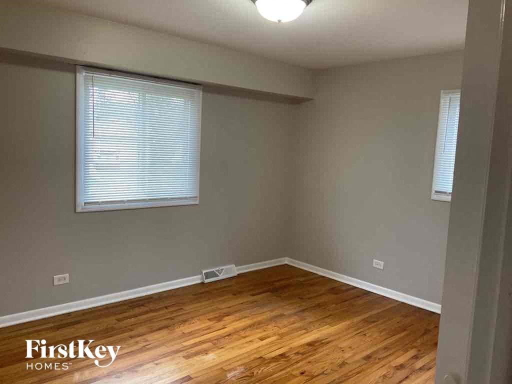 an empty room with a wooden floor and two windows