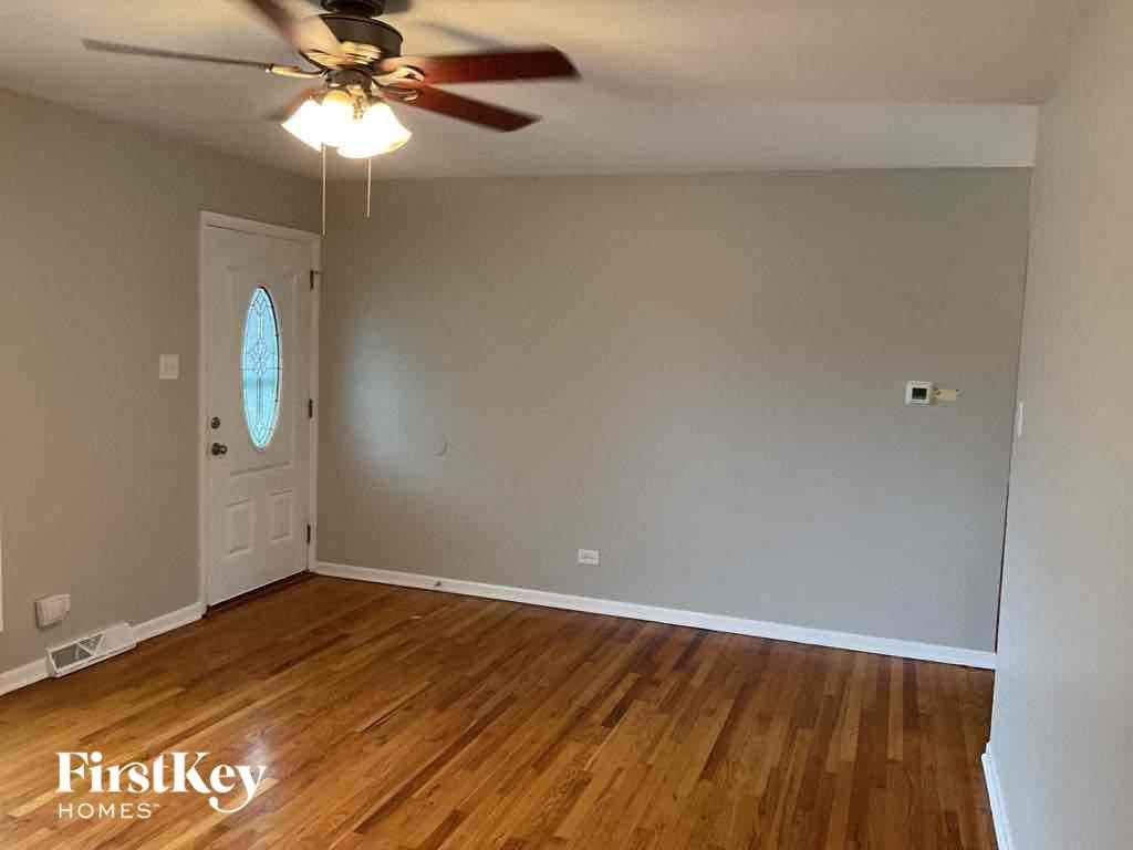 an empty living room with wood floors and a ceiling fan
