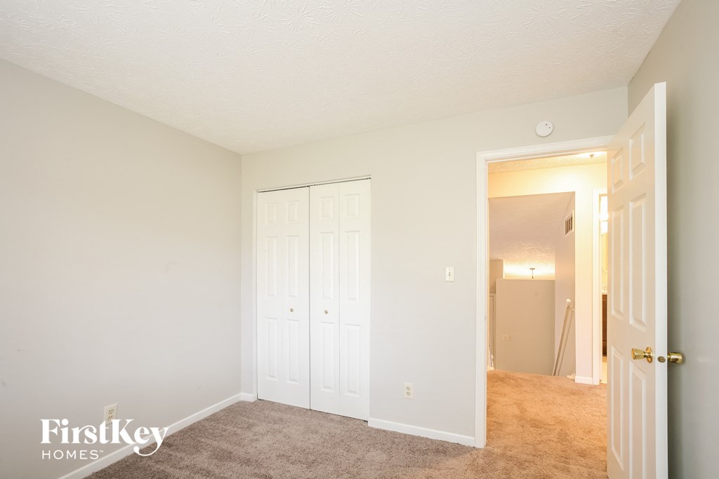 A bedroom with a white door and a white closet.