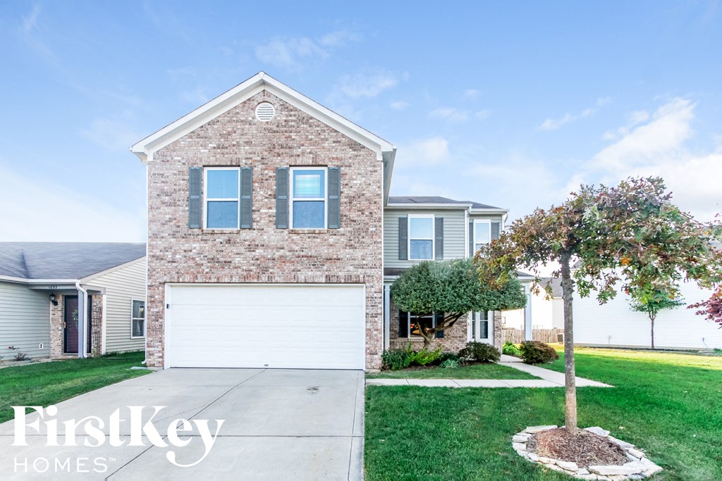 a brick house with a white garage door in front of a lawn