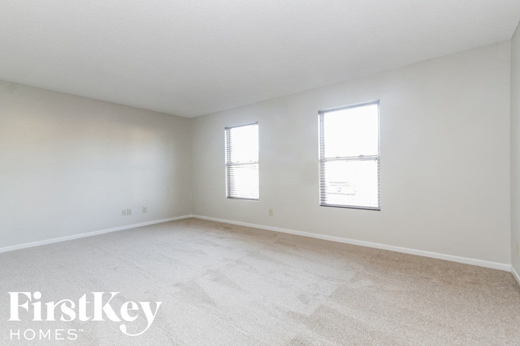a bedroom with white walls and white carpet and two windows