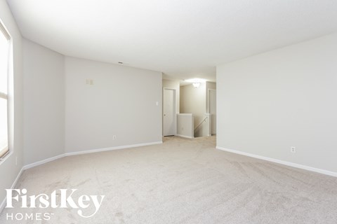 a spacious living room with white carpet and white walls