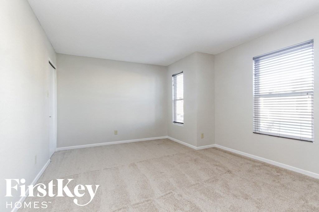 a spacious room with white walls and carpet and a window