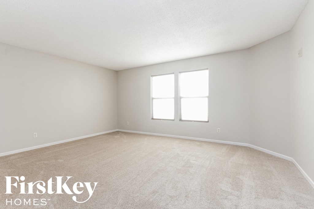 the living room of a home with a carpeted floor and two windows