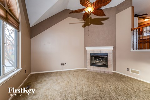 an empty living room with a fireplace and a ceiling fan