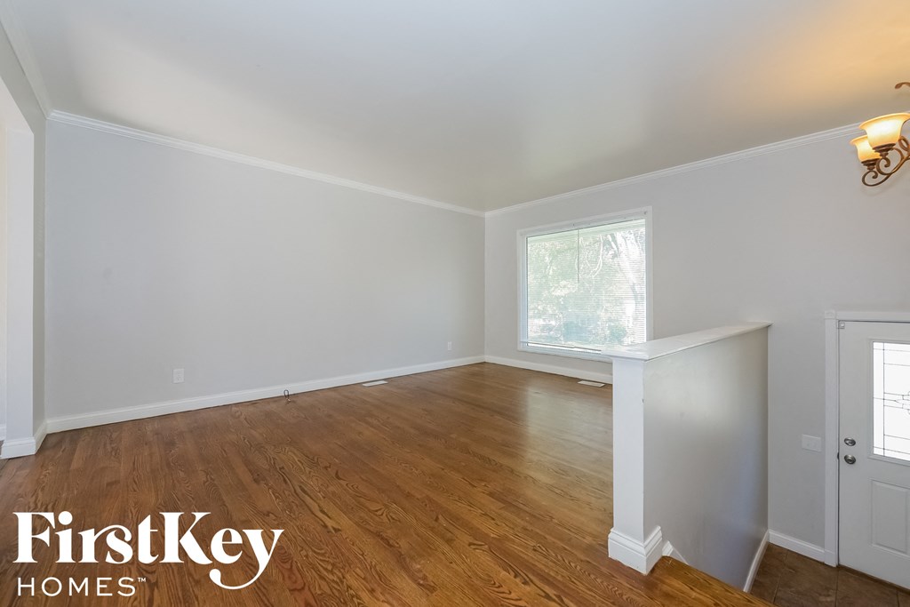 A room with wooden floors and white walls, with a window and a door visible.