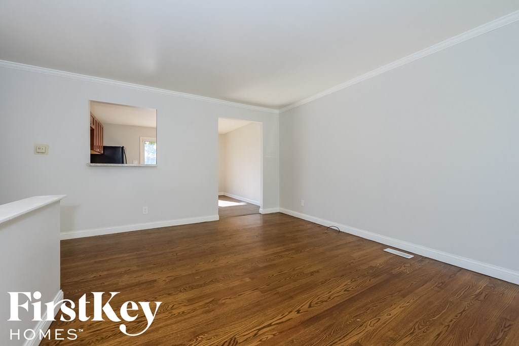 A room with wooden floors and white walls, with a mirror on the wall.