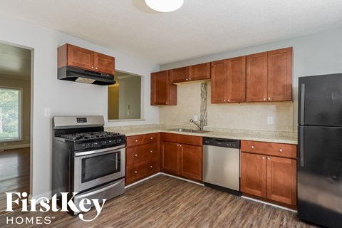 A kitchen with wooden cabinets and a black refrigerator.