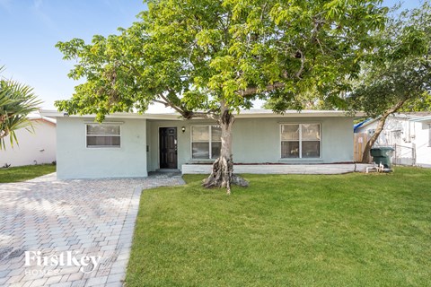 a small white house with a tree in the yard