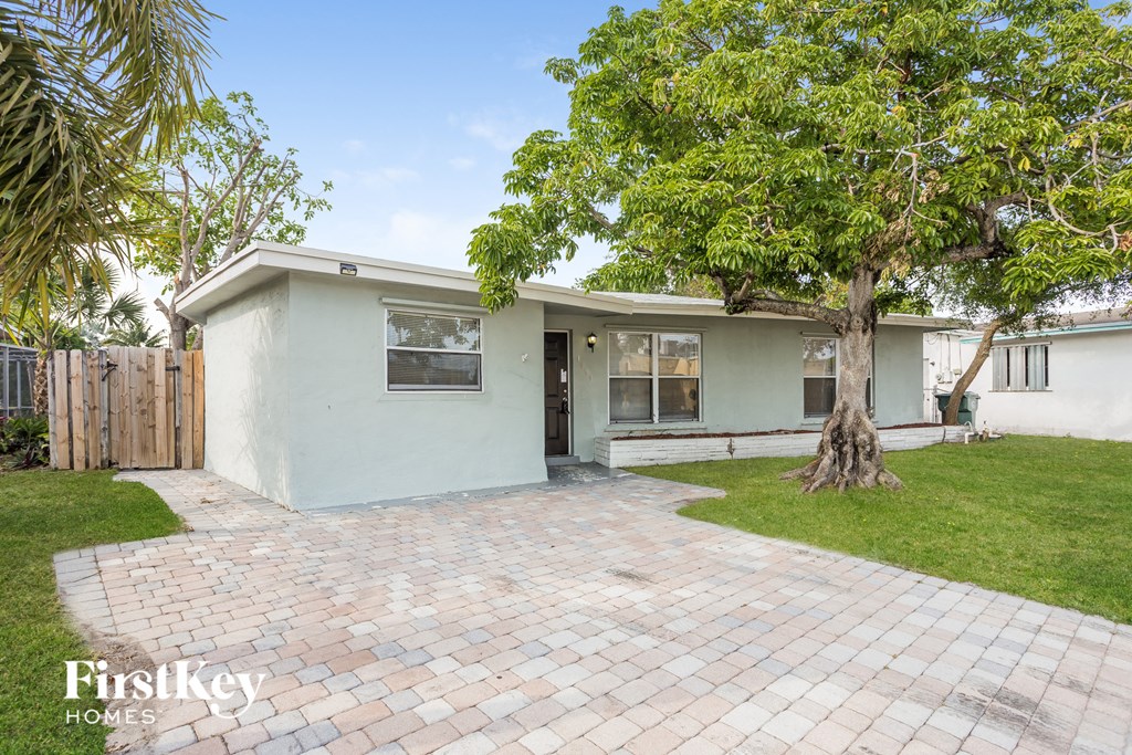 a small white house with a driveway and a tree