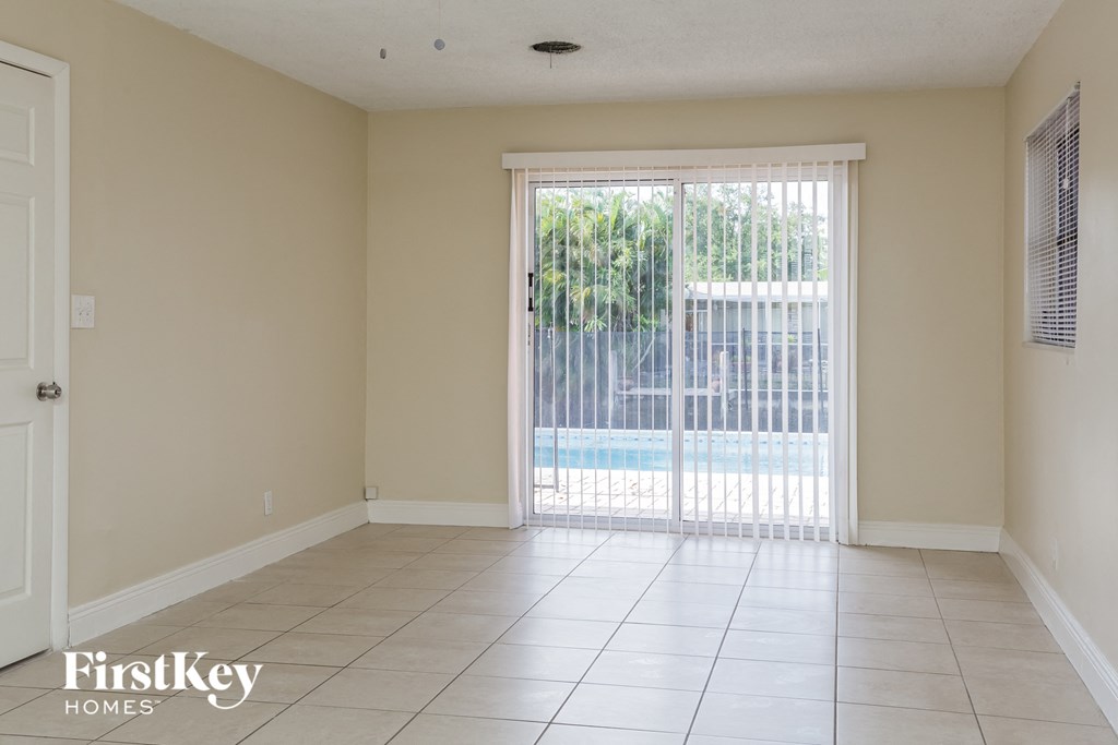 an empty living room with a sliding glass door to a pool