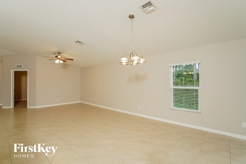 A spacious room with a ceiling fan and a chandelier.