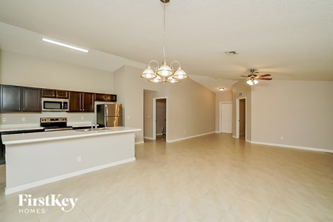 A spacious kitchen with a white countertop and a microwave built into the cabinetry.