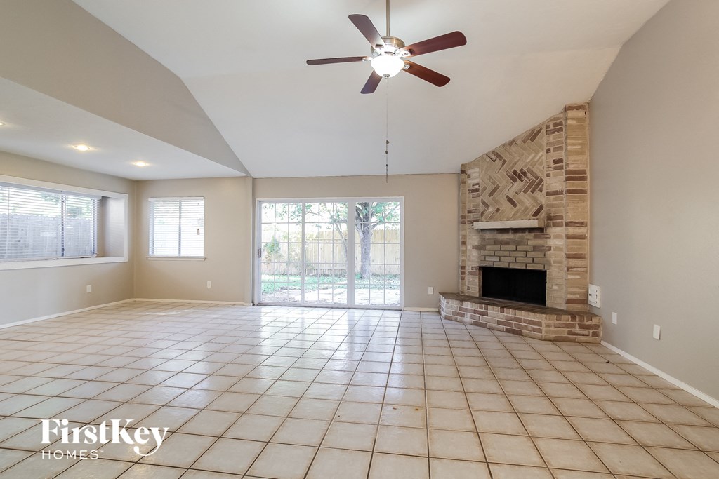 an empty living room with a fireplace and a ceiling fan