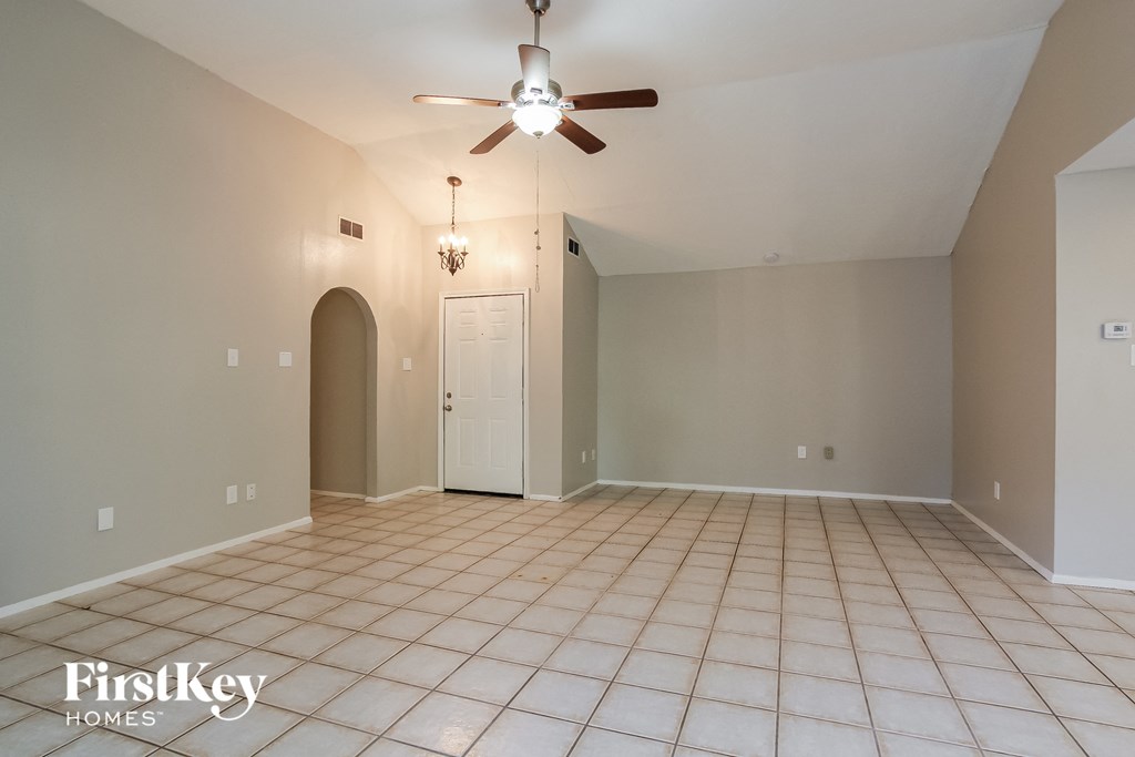 a empty living room with a ceiling fan and tiled floor