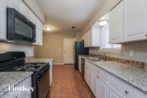 a kitchen with white cabinets and granite counter tops and black appliances