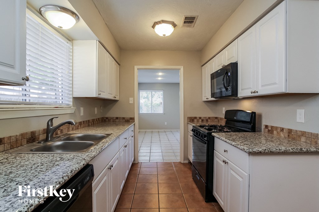 a kitchen with white cabinets and granite counter tops and black appliances