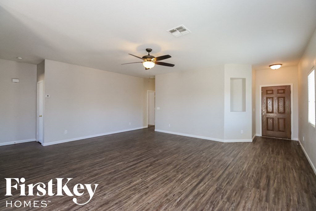 an empty living room with wood flooring and a ceiling fan
