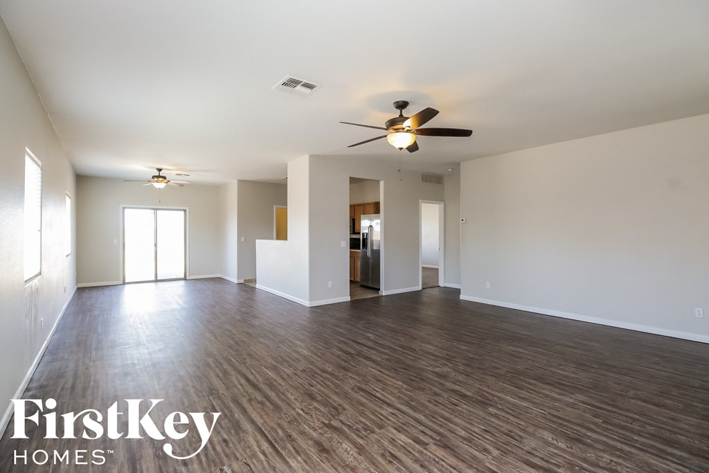 an empty living room with wood flooring and a ceiling fan