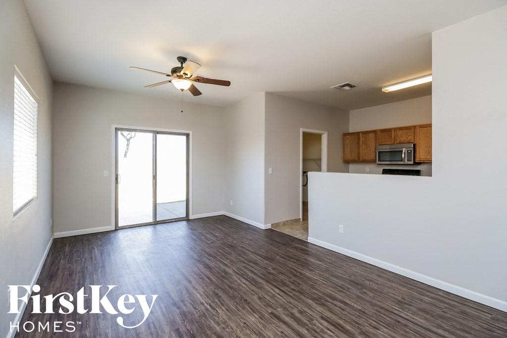 an empty living room with wood flooring and a ceiling fan