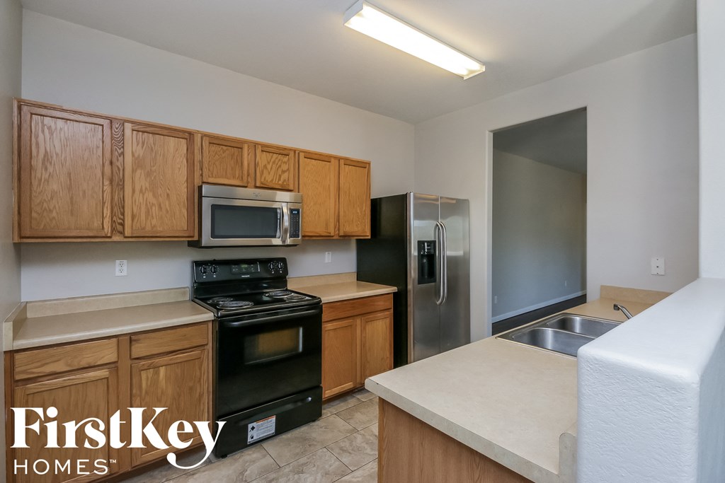 a kitchen with wooden cabinets and black appliances and a stainless steel refrigerator