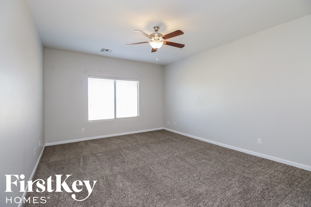an empty room with a ceiling fan and a window
