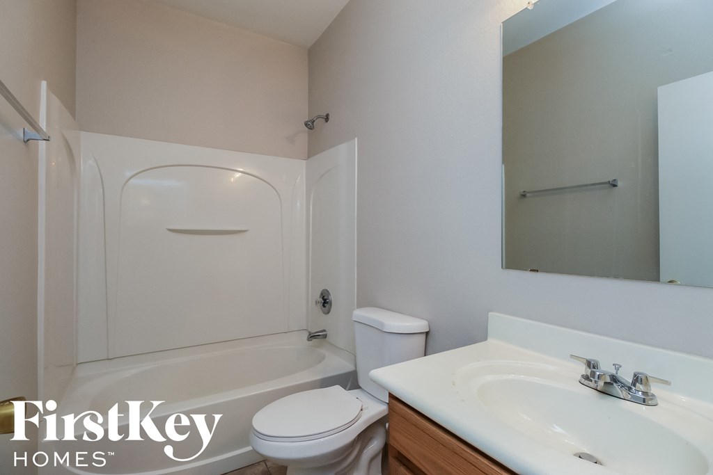 a white bathroom with a toilet sink and tub and a mirror