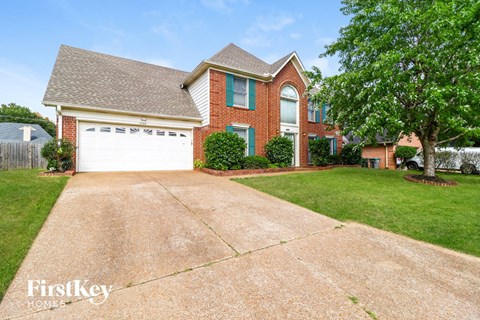 a large driveway in front of a brick house with a white garage door